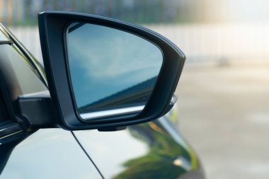 Araba aynası. Ayna dışbükey ve mavi renkli. Arabanın yan tarafına monte edilmiş ve çevreyi yansıtıyor. Arabanın cesedi arka planda kısmen görülebilir. Evde görüş bulanıklığı.