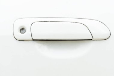 View of a used white car door handle. handle itself is a rectangular shape with a slight curve at the bottom. Round hole at the top end of the handle likely for a keyhole. Stains in the keyhole. clipart