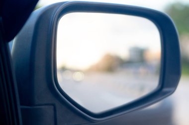 Yoldaki arabanın aynalı görüntüsü yolculuğun amacına doğru gidiyor. Bulanık ve kırık ışık yoldaki arabanın camında..