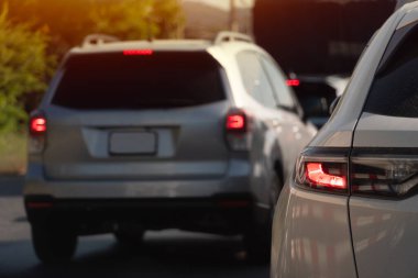 Traffic jam with several cars, mostly silvergray, seen from behind. Brake lights are illuminated. Blurred background suggests movement or slow traffic. clipart