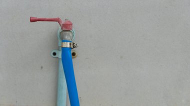 Su püskürtücü için hortum kıskacı. Hortumun musluktan akmasını önler. Çimento duvarına su boruları yerleştirilmiş..