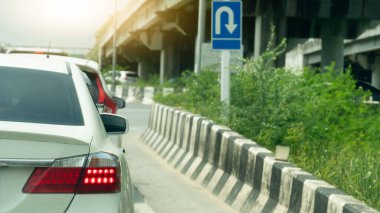 Yoldaki arabaların nakliyesi. Ön vagonların U dönüşü yapması için açık ışık freni. Seyahate ya da işe gidiyorum. Asfalt yolda. Beton köprü ile U-Dönüşü panosunu imzala.
