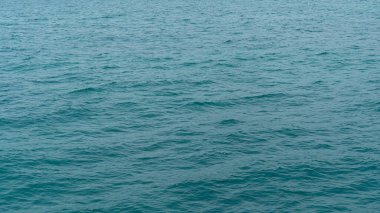 Yumuşak dalgalı okyanus suyu. Su, bir deniz ya da büyük bir su kütlesi olduğunu gösteren istikrarlı bir deniz mavisi ya da mavi renk gibi görünüyor. Su dokusuna ve ince hareketlere odaklan..