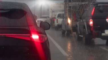 Şiddetli yağmurlu bir zamanda aracın taşınması soyut ve bulanık. Koyu renk arabanın arka tarafında trabzanda ışık freni var. Fren lambası parlıyor ve yağmurun yansıması. Yoldaki diğer arabaların trafik sıkışıklığı.