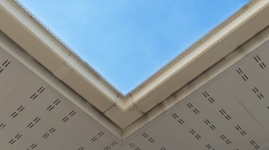 Çatı katının manzarası altında. Beyaz PVC kuluçka ve drenaj kanalları. mavi gökyüzünün arkaplanı.