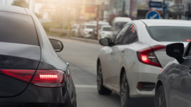 Fren lambalı siyah arabanın arka tarafında. Bir kavşakta trafik ışığında dur. Şehirdeki yoğun saatlerde trafik sıkışıklığı. Tayland 'da gündüz yolları.