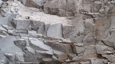 Düz olmayan bir yüzeyi olan gri taş bir doku. Çatlak ve katmanlı kaya oluşumlarının doğal bir arka planını gösteriyor. Ayrıntılı çekim jeoloji veya mimari tasarım projeleri için idealdir..