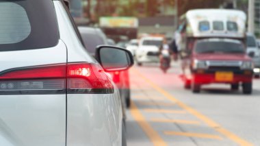 Beyaz arabanın arka tarafında fren lambası açık. Arabanın stop lambasında kırmızı ışık hızı. Tayland 'ın kentsel yollarında yoğun arabaların durumu.