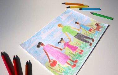 Renkli kalemlerle çocuk çiziminin açısal fotoğrafı. Resim aileyi gösteriyor. Anne, baba, erkek, kız, köpek yürüyor. Afro-Amerikan görünümlü anne. Babam beyaz. Kalemleri doldur. Beyaz arkaplan.