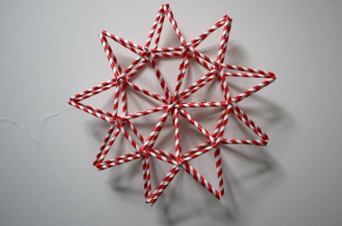Yıldız. El yapımı ev dekorasyonu. Kırmızı ve beyaz çizgili çizgilerden. Kamış içmek. Beyaz ipliği var. Beyaz arka planda izole edilmiş. Gölgesi var. Geometrik şekil. Noel, karnaval, parti.