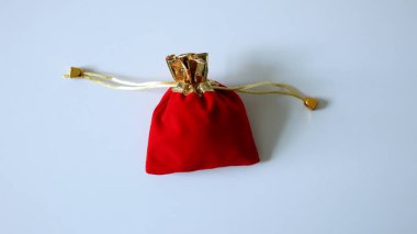 Altın telli küçük kırmızı bir çanta. Beyaz arka planda izole edilmiş. Arka planda yer alıyor. Fotoğraf. Hediye. Ivır zıvır.