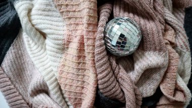 Disko topu yumuşak malzemelere dayanır. Örgü kumaş kaotik olarak farklı kıvrımlara katlanır. Farklı örgü dokuları. Ve farklı renkte kumaşlar. Gri, pembe, beyaz Mocha Mousse. Fotoğraf.