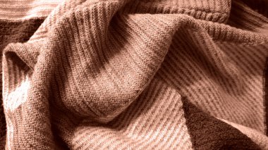 Arka plan örülmüş kumaşlarla dolu. Mocha Mousse renginin farklı tonlarında. 2025 yılının rengi. Kumaşın kıvrımları var. Örgünün farklı dokusu