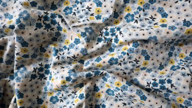 Baskılı kumaştan yapılmış fotoğraf arkaplanı. Bir sürü kaotik kıvrım. Farklı çiçek ve yaprakların süsü. Basit şekilli çiçekler. Mavi, sarı, şeftali, siyah renklerin farklı tonlarında. Beyaz arkaplan.