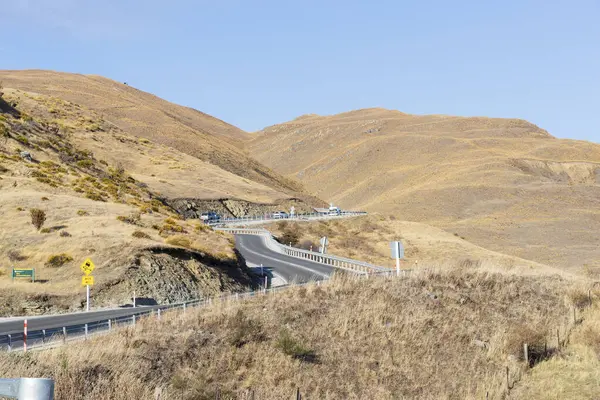 Pisa Koruma Alanı, Yeni Zelanda 'nın dağlık tepelerinde arabalar, yol işaretleri ve gözlem noktalarıyla dolambaçlı yol. Tepeleri kaplayan alp bitkilerinin olduğu resim gibi bir bahar manzarası..