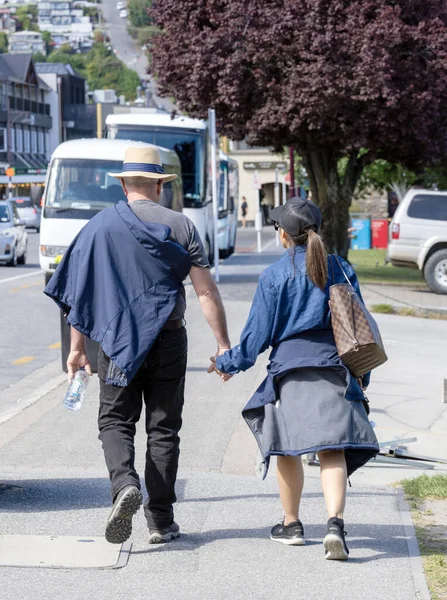 Queenstown, Yeni Zelanda - 26 Kasım 2023: Sevgi dolu bir çift, sakin bir şehir ortamında, sevgi ve dostluğu somutlaştırarak, bir şehir caddesinde el ele yürür.