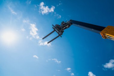 İnşaat telsizcisi, çatalı kaldırdı ve mavi gökyüzüne doğru kaldırdı.