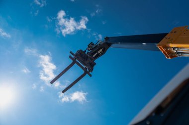 İnşaat telsizcisi, çatalı kaldırdı ve mavi gökyüzüne doğru kaldırdı.