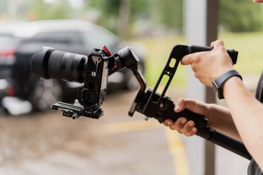 Elinde kamera olan bir adam uzaktan kumandayı tutuyor. Profesyonel fotoğrafçı, sabit dengeleme kitinde dijital kameranın fotoğrafını çekiyor.