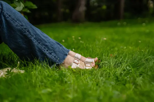 Kot pantolonlu bir kadın ve parktaki çiçekli bir gömlek.