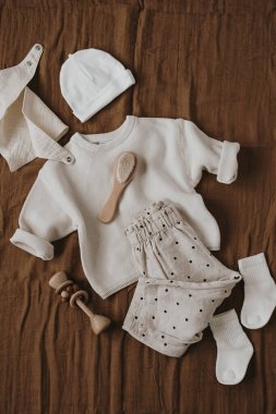 Tatlı Hygge pastel giysileri, yeni doğan bebek için aksesuarlar. Muslin önlüğü, kazak, koşucular, çoraplar, fırça, kahverengi çarşaflı şapka. Estetik lüks bebek mağazası, alışveriş konsepti. Flatlay, üst görünüm