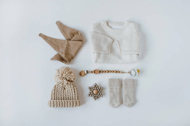 Flatlay estetik İskandinav bebek kıyafetleri, aksesuarlar, beyaz arka planda oyuncak kolajı. Moda, zarif, nötr, pastel renkli bebek moda seti. Üst görünüm