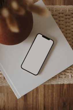 Boş ekran cep telefonu ve rattan taburesi var. Düz yerde, üst tarafta. Boşluk düzenleme şablonunu kopyala.