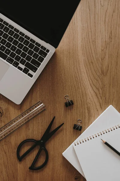 Laptop, defter, kahverengi ahşap masa zemininde kırtasiye malzemesi. Düzlük, üst görünüm estetik minimal serbest yazar, blog yazarı ofis çalışma alanı