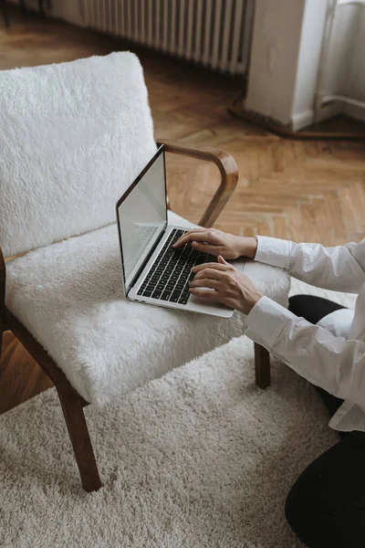 Aesthetic minimalist home office workspace desk. Person using laptop computer on comfortable chair. Work, online business, online shopping concept