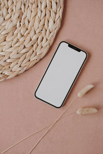 Flatlay of blank clipping path screen mobile phone. Aesthetic home office desk workspace with dried grass stalks. Lady, girl boss business, work, blog template with mockup space. Flat lay, top view