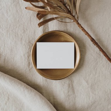 Estetik bir bohem düğün davetiyesi şablonu ve fotokopi alanı. Altın tepside kağıt kart, nötr bej keten battaniyede kurutulmuş protea çiçeği.