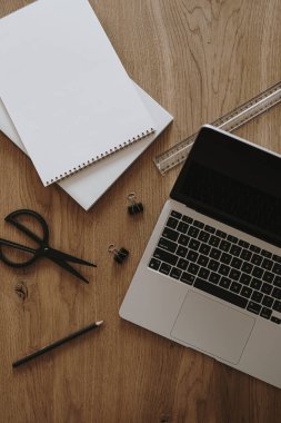 Laptop, defter kahverengi tahta masa arkasında. Düzlük, üst görünüm estetik minimal serbest yazar, blog yazarı ofis çalışma alanı