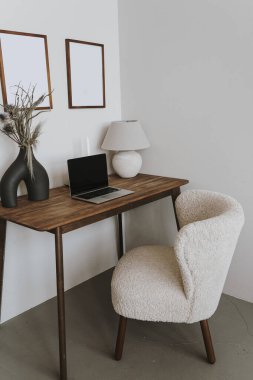 Laptop bilgisayarı, masa, sandalye, vazoda kurutulmuş çiçek buketi ve lambası olan zarif bir bohem çalışma alanı. Freelancer merkez ofis çalışma alanı. Evde çalış.