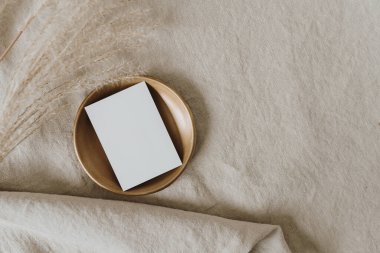 Pirinç tabakta boş kağıt kağıdı, nötr bej bezde pampa otu, buruşuk çarşaf bezi. İş planı. Üst görünüm, düz uzanan minimalist estetik lüks bohem ticari markalaşma kavramı