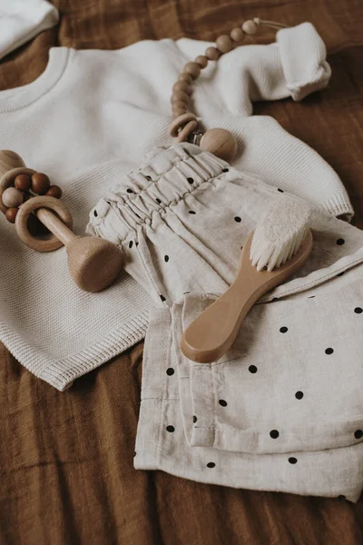 Aesthetic Scandinavian newborn baby clothes, accessories, toys on brown background. Trendy elegant luxury infant set. Top view