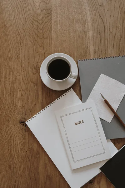 Aesthetic minimalist home office desk workspace on wooden background. Notebook, coffee cup, pen. Business, work concept for blog, website, social media.