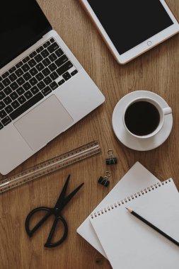 Estetik ofis masası çalışma alanı. Diz üstü bilgisayar, tablet, tahta masadaki defter. Etkileyici yaşam tarzı blog arka planı