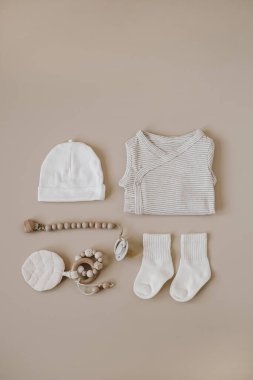 Flatlay estetik İskandinav bebek kıyafetleri, aksesuarlar, renksiz pastel arka planda oyuncak kolajı. Çok şık bir bebek giysisi. Üst görünüm