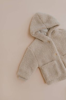 Sıcak kış çocuk ceketi. Bej arka planda bebek giysisi. Moda İskandinav çocuk kıyafetleri. Düz yatış, üst görünüm.