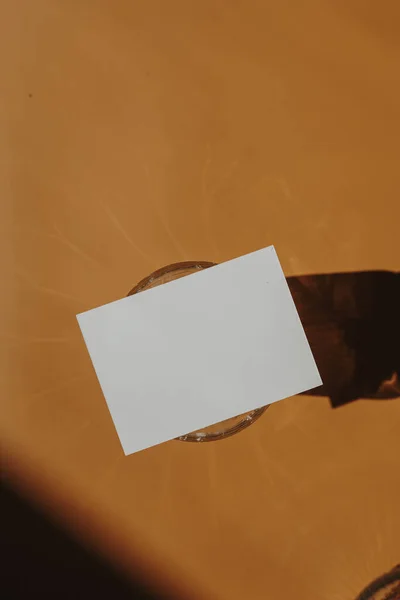モックアップコピースペース ガラス オレンジの背景に日光の影を持つ空白の紙のシートカード 審美的なボヘミアン最小限のビジネスブランドテンプレート フラットレイアウト トップビュー — ストック写真