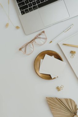 Estetik ofis masası çalışma alanı. Dizüstü bilgisayar, fotokopi alanı olan boş kart kağıdı, beyaz arka planda kırtasiye malzemesi. Sosyal medya ve blog için ev kompozisyonu üzerine zarif minimalist çalışma