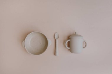 Silikon kase, kaşık, küçük bebek için yiyecek ve içecek seti. Açık renkli pembe arka plan. Düz yatış, üst görünüm