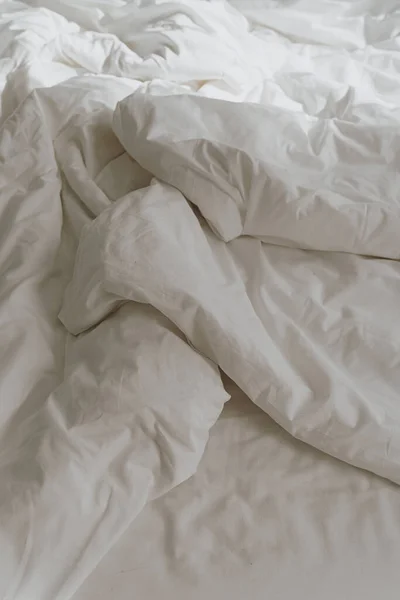White crumpled bed linens with sunlight shadows. Morning in bed concept