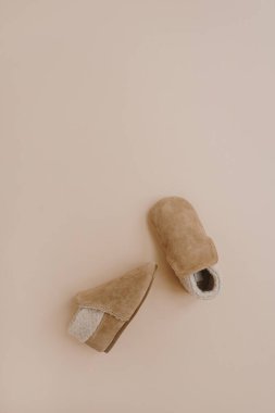 Sıcak kış çocukları için mini patik. Tarafsız bej arka planda bebek ayakkabıları. Moda İskandinav çocuk kıyafetleri. Düz yatış, üst görünüm.