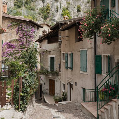 Kırsal İtalyan mimarisi. Geleneksel tarihi Avrupa kır binaları. Ahşap pencereleri, çiçekleri ve çiçek açan ağaçları var. Estetik yaz tatili seyahat kavramı