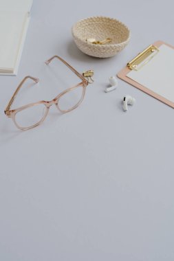 Not defteri, gözlük, kablosuz kulaklık. Boş kopyalama alanı. Pastel arka planda estetik stil kadın ofis kırtasiyesi aksesuarları