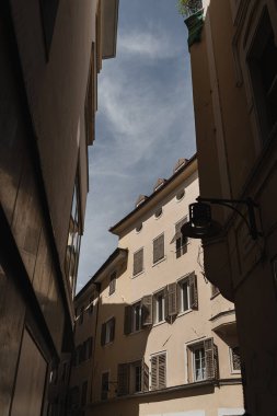 Eski tarihi İtalyan mimarisi. Geleneksel Avrupa eski kasaba binaları. Ahşap pencereler, kepenkler ve güneş ışığı gölgeli renkli pastel duvarlar. Estetik yaz tatili seyahat geçmişi