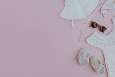 Pembe arka plandaki bebek için bir takım şirin yaz kıyafetleri ve aksesuarları. Düz yatış, küçük bebek için şık moda koleksiyonu manzarası