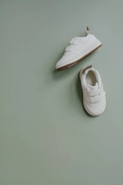 子供の赤ちゃんのための白いスニーカーの靴 北欧の子供服の平らなレイアウト 審美的な中性パステルグリーンの背景 — ストック写真