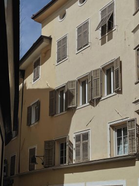 İtalya 'daki eski tarihi mimari. Geleneksel Avrupa eski kasaba binası. Ahşap pencereler, kepenkler ve güneş ışığı gölgeli renkli pastel duvarlar. Estetik yaz tatili seyahat geçmişi